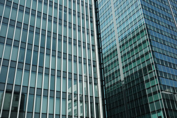 Naklejka premium Modern glass facade of corporate office buildings with reflections background. global business, financial districts, corporate success, urban development, and contemporary office architecture.