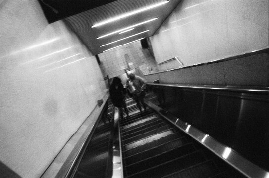 Anonymous Figures Rising on Subway Escalator