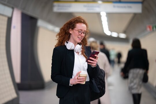 Woman walking in subway corridor using smartphone