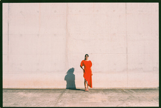 Woman in red dress on concrete wall