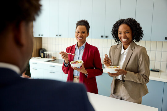 Smiling elegant women eating a quick meal in a corporate canteen
