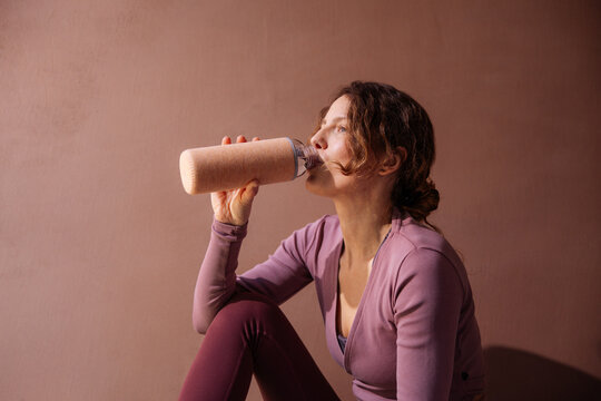 Woman Drinking Smoothie From Bottle After Workout