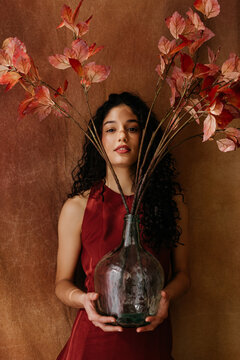 Woman holding large glass vase with autumn leaves