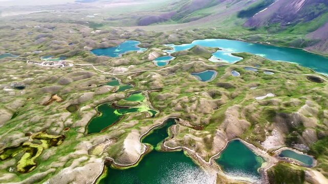 Aerial view of Tulpar Lake and numerous turquoise ponds scattered across the rolling green hills of the Alay District, Osh Region, Kyrgyzstan.
