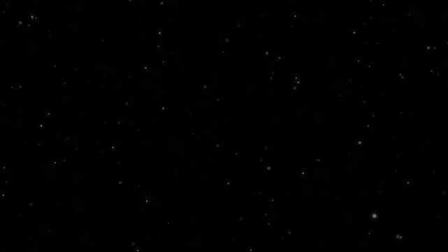 Soft shimmering particles resembling snow or ash gently drifting and falling on dark background overlay