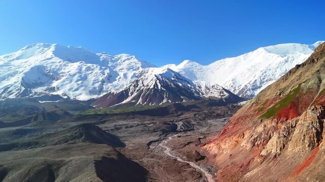 Aerial view of Base Camp for Peak Lenin with snow-capped peaks and red rock formations in the valley of Chong-Alay District, Osh Region, Kyrgyzstan.