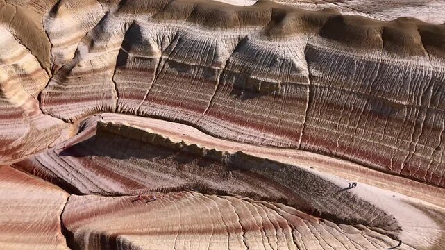 Aerial view of striped rock formations and layered sedimentary canyons in the desert Kyzylkum, Mangystau Region, Kazakhstan.