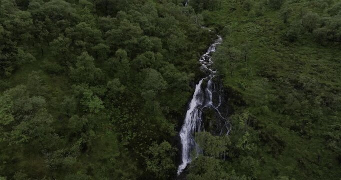 Thin tall waterfall cascading down mountainside in Scotland