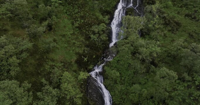 Tall cascading waterfall in the forest on a mountainside