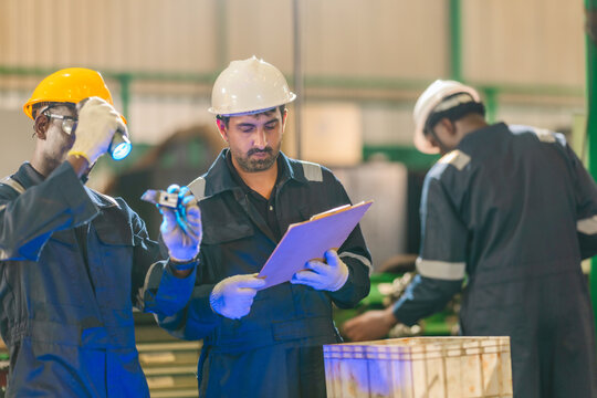 Factory technician inspecting auto parts, metal rod at machining station