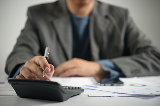 Corporate executive lifestyle showing business person evaluating company financial report paperwork calculating profit revenue and auditing market strategy graph at office desk