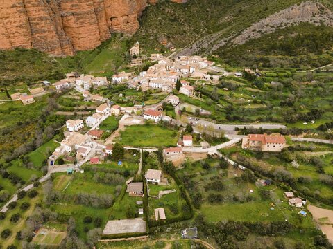 Aerial view of a picturesque village surrounded by green hills and striking orange rocks, aerial view, Las Pe&ntilde;as de Riglos, As Penyas de Riglos, Mallos de Riglos rock formation, Huesca, Aragon, Spain