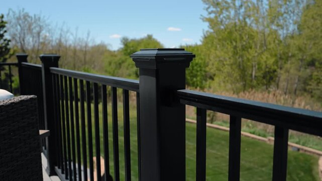 Modern elevated backyard deck attached to suburban house featuring black metal railings, outdoor stairs in residential neighborhood