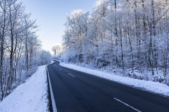 Snow-covered road winds through a wintry forest, hoarfrost in Unterallg&auml;u, Bavaria, Germany