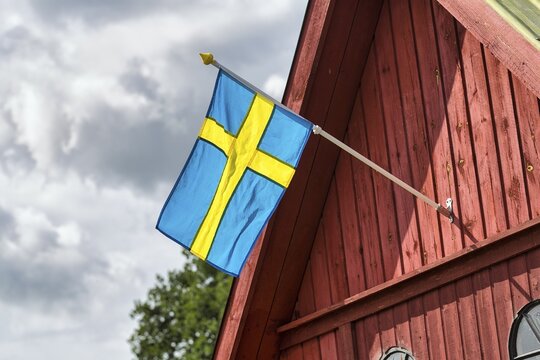 Swedish flag, national flag on a red wooden gable, Swedish house, Gotland Island, Sweden