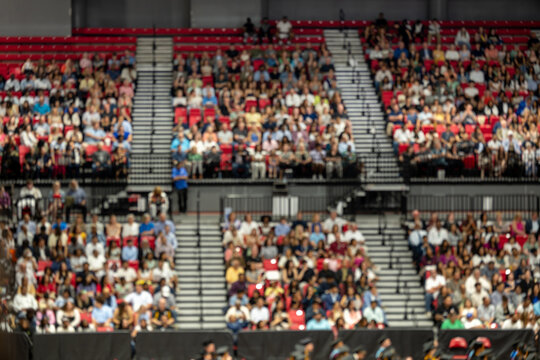 Blurred crowd of spectators sitting in stadium stands during large public event with shallow depth of field and abstract audience background
