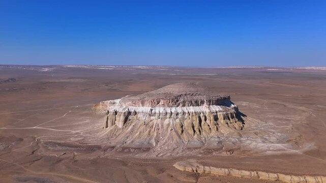 Aerial view of the majestic Sherkala mountain mesa rising from the arid desert plains under a clear blue sky Mangystau Region, Kazakhstan.