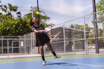 Obraz premium Pickleball sports player, woman active hitting ball on outdoor court. Fitness exercise and healthy lifestyle recreation game during sunny day.