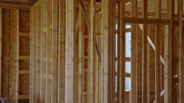 Wood framing inside a new residential house under construction with unfinished walls and structural support beams. Wooden frame