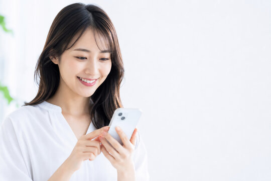 笑顔でスマートフォンを操作する若い日本人女性 Generative AI
