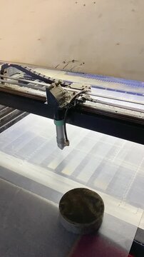The head of the laser machine cuts acrylic sheets in the workshop