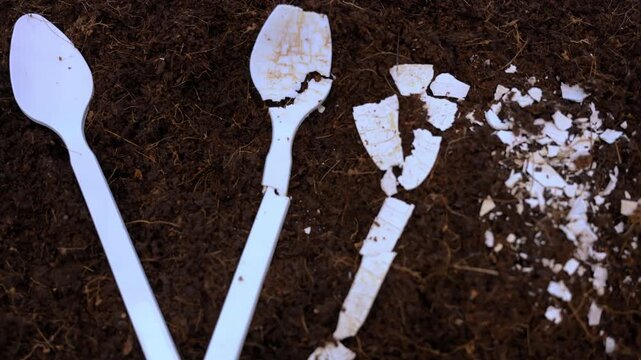White plastic spoon breaking down in soil showing environmental pollution, plastic waste decomposition, and ecological damage concept
