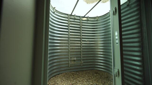 Modern corrugated metal window well attached to residential basement featuring protective cover, ladder access, and gravel drainage system outside suburban home