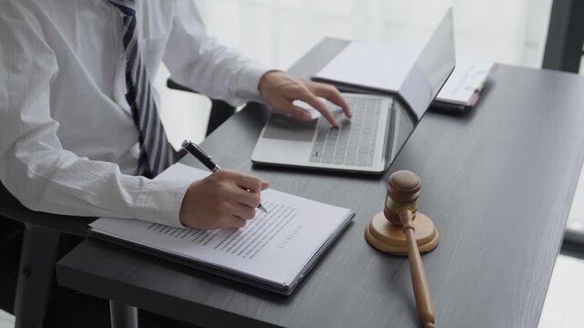Lawyer checking documents and typing on laptop