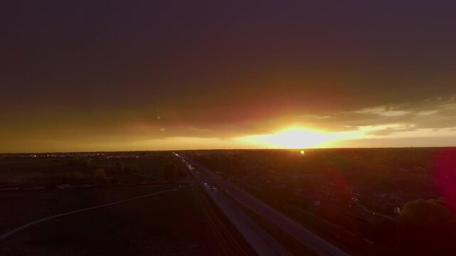 Golden sunset over suburban city skyline with heavy clouds and glowing orange sky. Evening with sun rays breaking through storm clouds