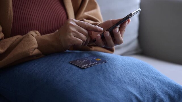 Asian mature woman using credit card booking ticket online on smartphone