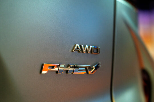 Penang, Malaysia - May 2, 2026: Macro close-up of the chrome AWD and PHEV "plug-in hybrid electric vehicle" emblem on the bodywork of an Omoda C9 premium SUV.