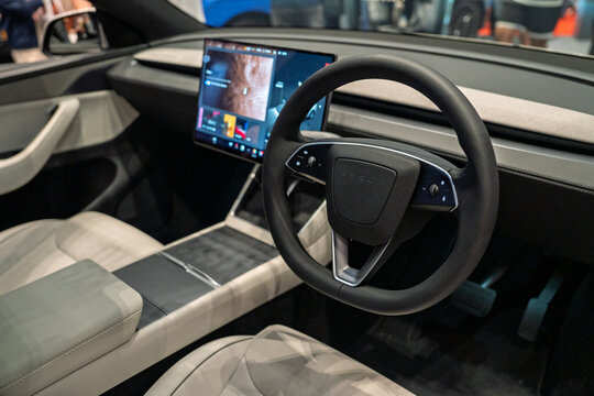Penang, Malaysia - May 02, 2026: An interior shot of a right-hand drive Tesla electric vehicle cabin, focusing on the minimalist dashboard, white leather seats, central touchscreen and steering wheel.