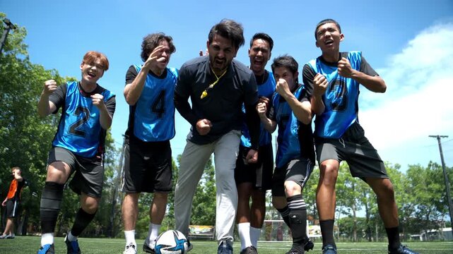 Soccer coach and players celebrating together after training, showing excitement, achievement, and strong team spirit on an outdoor football field