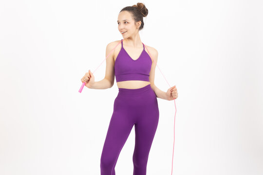 Young fitness woman holding pink jump rope expander over shoulders