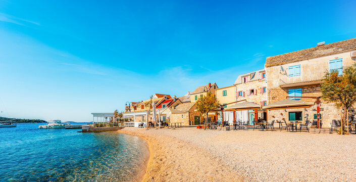 Scenic coastal promenade and the old stone town of Primosten under a clear blue sky, Dalmatia, Croatia.