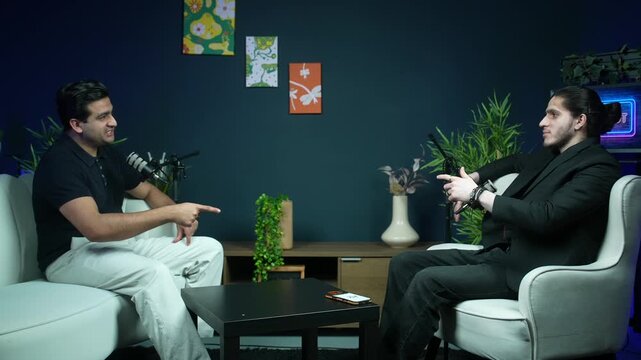 Two men having an animated conversation with microphones in a modern studio setup