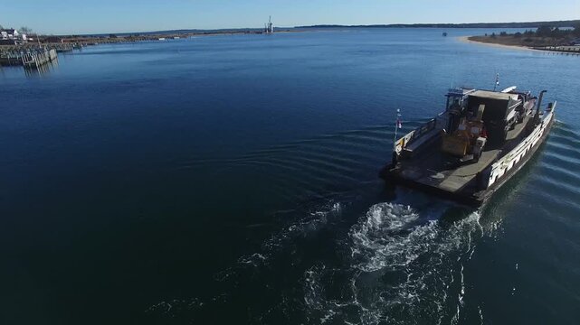 Aerial view of Chappy Ferry crossing the harbor with a vehicle on board near waterfront buildings in Edgartown, Massachusetts, United States.