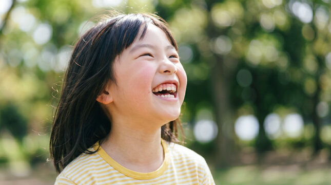 公園で空を見上げる可愛い女の子 芝生の上で笑顔