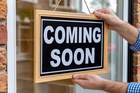 Person hanging coming soon sign on storefront window