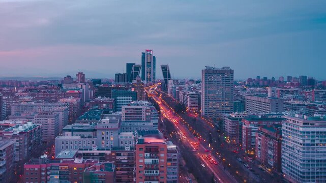Time lapse aerial view of Madrid city skyline at sunset with car traffic lights and modern skyscrapers in Spain.