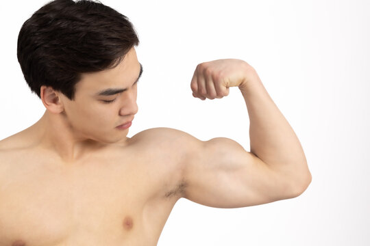 Shirtless man flexing his bicep and looking at it