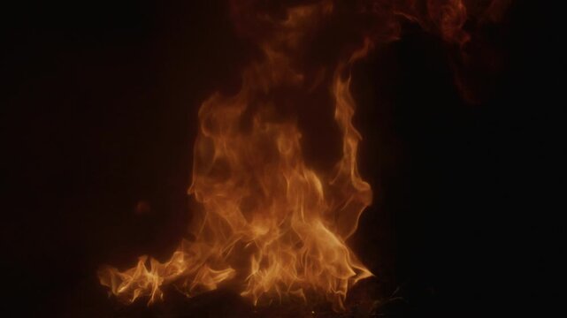 Burning flame texture ideal for powerful overlays. Inferno effect with vivid swirling flame. Fire abstract background featuring dynamic flame shapes. Glowing flames rising on deep black slow motion.