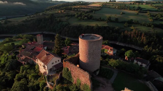 Aerial shot around Saint Jean Saint Maurice medieval tower revealing tghe loire ruver at sunrise near Roanne city in Loire departement, Auvergne Rhone Alpes region, France