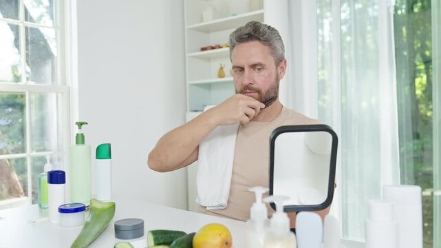 Bearded man combing beard after shower. Bearded man styling beard for clean look. Bearded man combing beard in morning light.