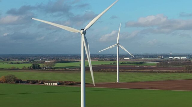 Drone shot tracking eco friendly wind energy windmills integrated inside green agricultural farming fields