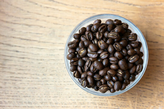 A bowl of 100% Kona Peaberry coffee beans from Hawaii on a table