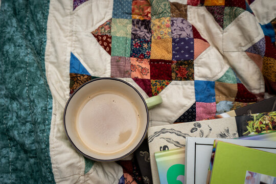 cup of coffee with books on a bed