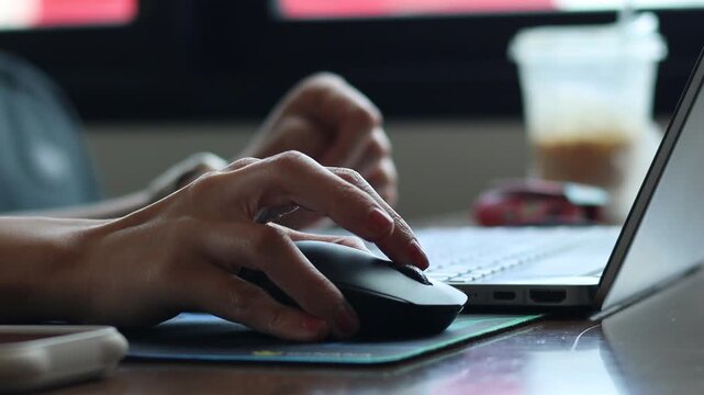 Close-up video of a businesswoman's hand using a wireless computer mouse while working on a laptop at a desk, representing freelancing, remote work, digital marketing, and modern office productivity.