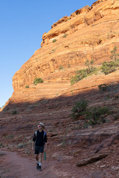 Young man hikes a desert trail near red rocks