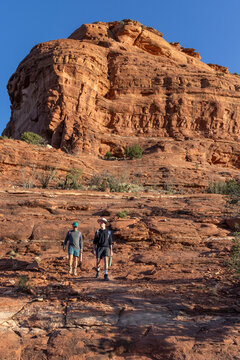 Two men hiking down a red rock formation vertical